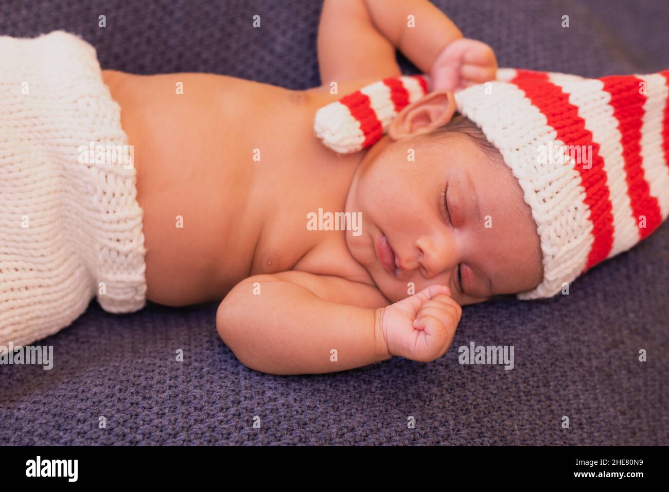 Le nouveau-né allongé dans un chapeau rayé est endormi avec ses mains clastées Banque D'Images
