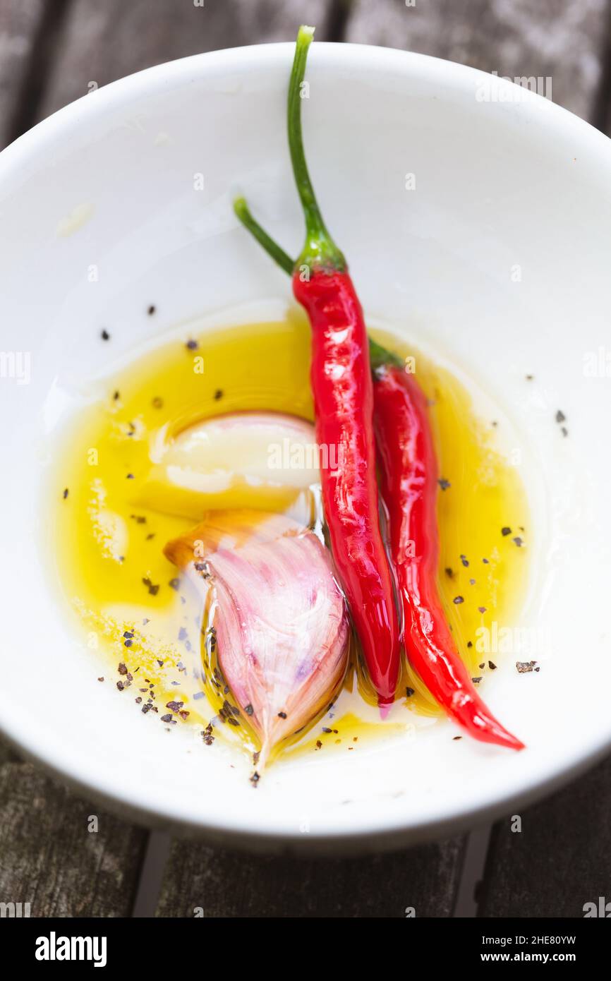 Huile d'herbes aromatiques avec piments rouges frais, ail et poivre Banque D'Images