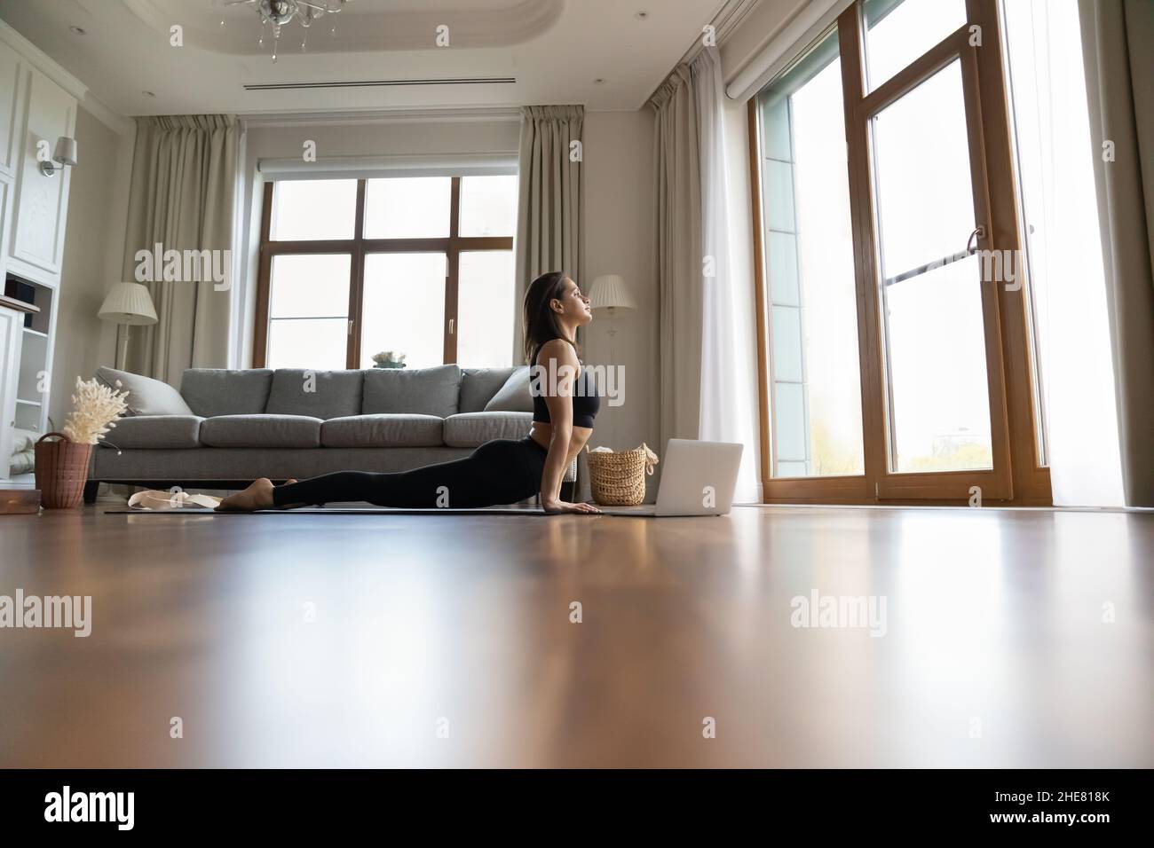 Femme calme pratiquant le yoga à la maison, consultant en vidéo leçon en ligne Banque D'Images