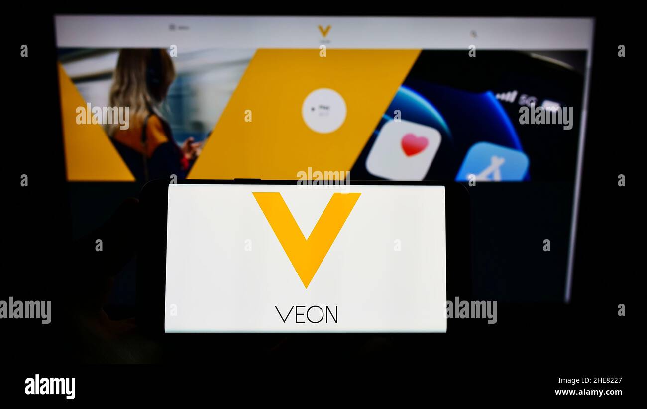 Personne tenant un smartphone avec le logo de la société de télécommunications VEON Ltd. À l'écran devant le site Web.Mise au point sur l'affichage du téléphone. Banque D'Images
