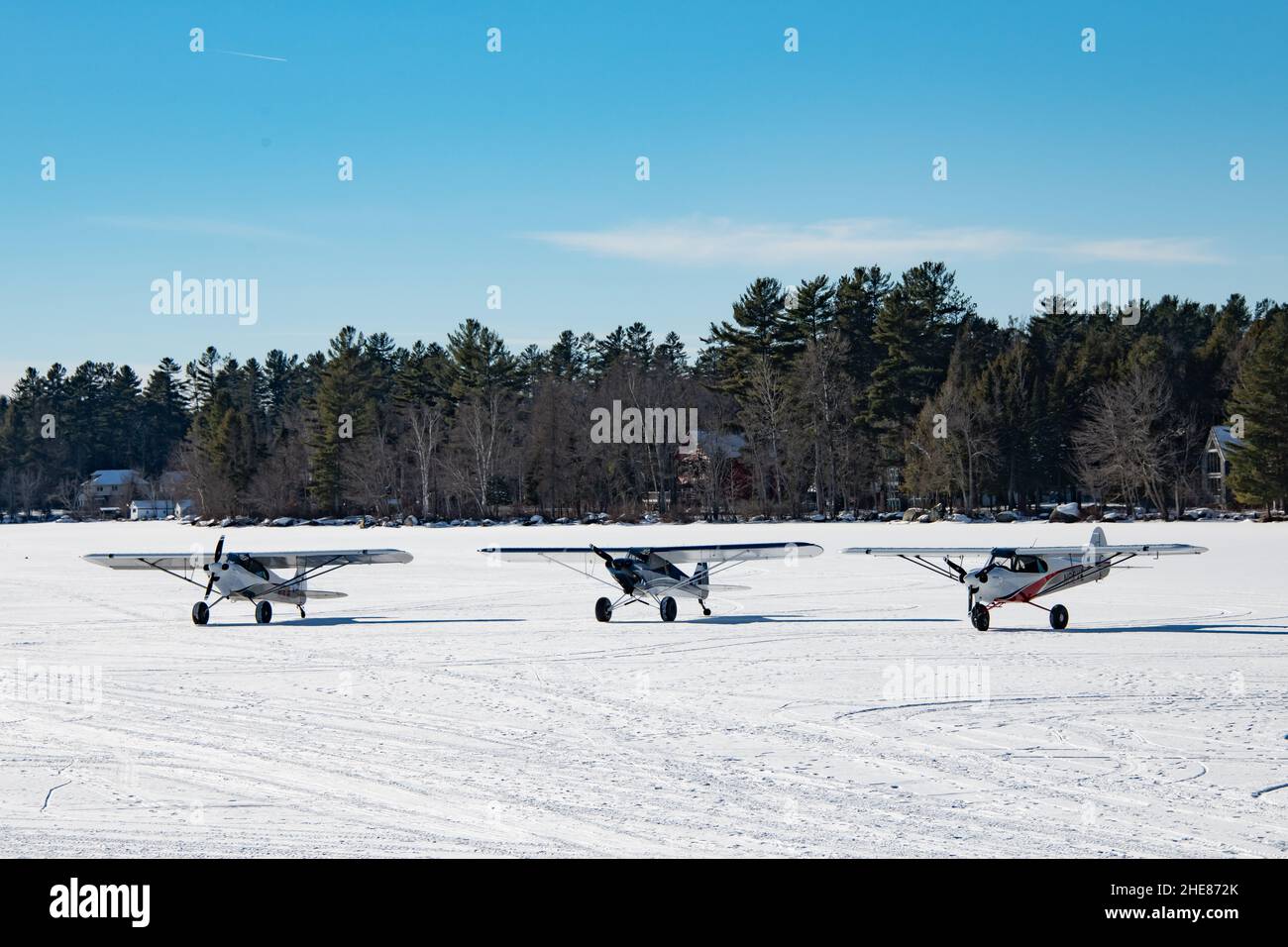 Trois avions à moteur unique Cub Crafter garés sur la neige et la glace sur le lac Pleasant dans les montagnes Adirondack, NY États-Unis Banque D'Images