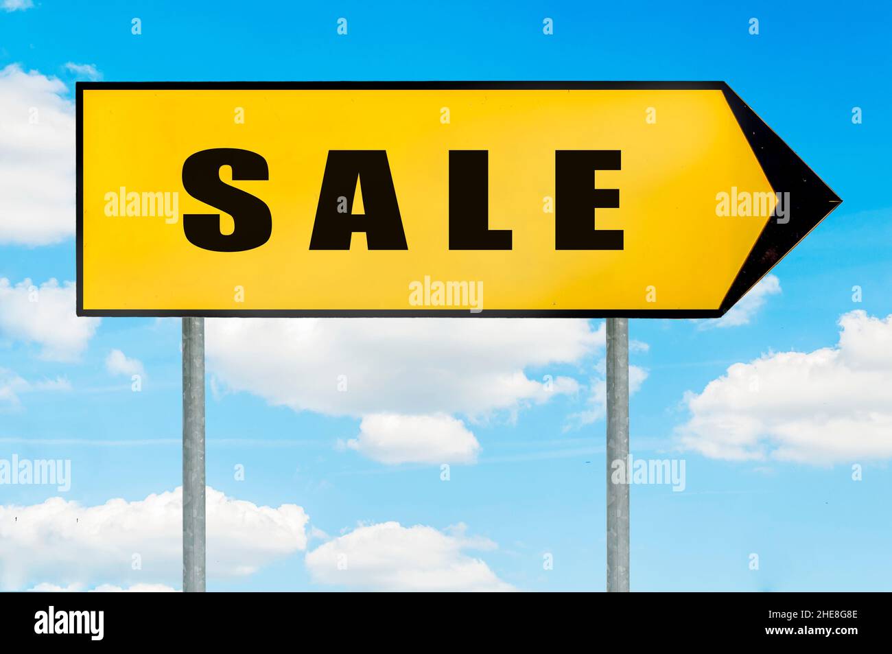 Signe de vente - panneau de route jaune avec flèche pointant vers la droite contre ciel bleu nuageux Banque D'Images