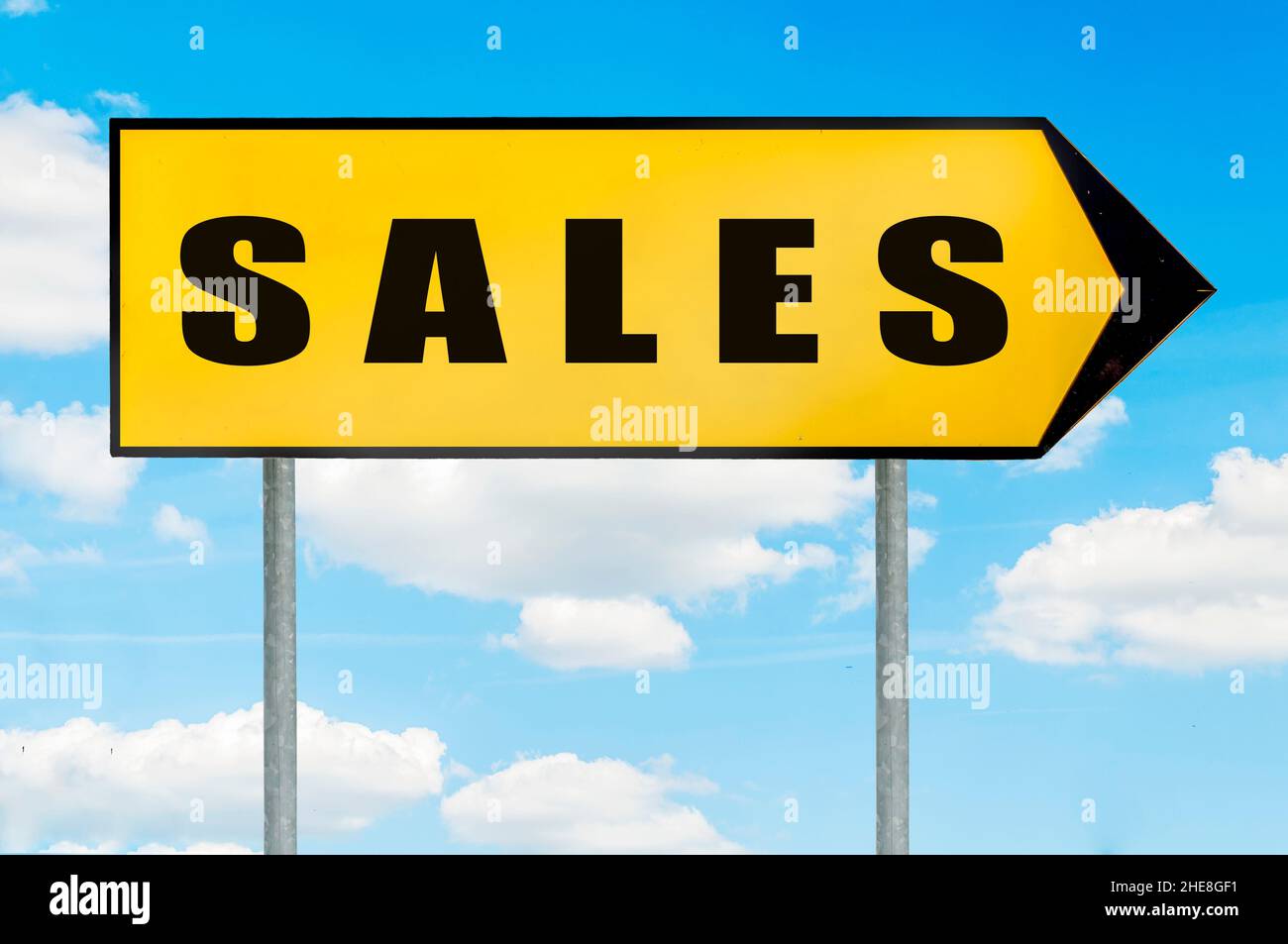 Signe de vente - panneau de route jaune avec flèche pointant vers la droite contre ciel bleu nuageux Banque D'Images