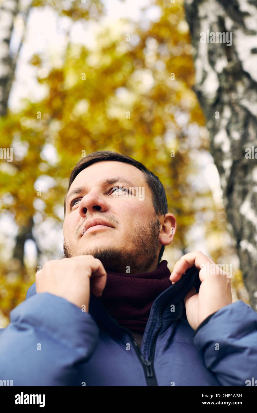 Portrait d'un beau homme dans la forêt d'automne dans une veste et une écharpe en duvet.Vue avant. Banque D'Images