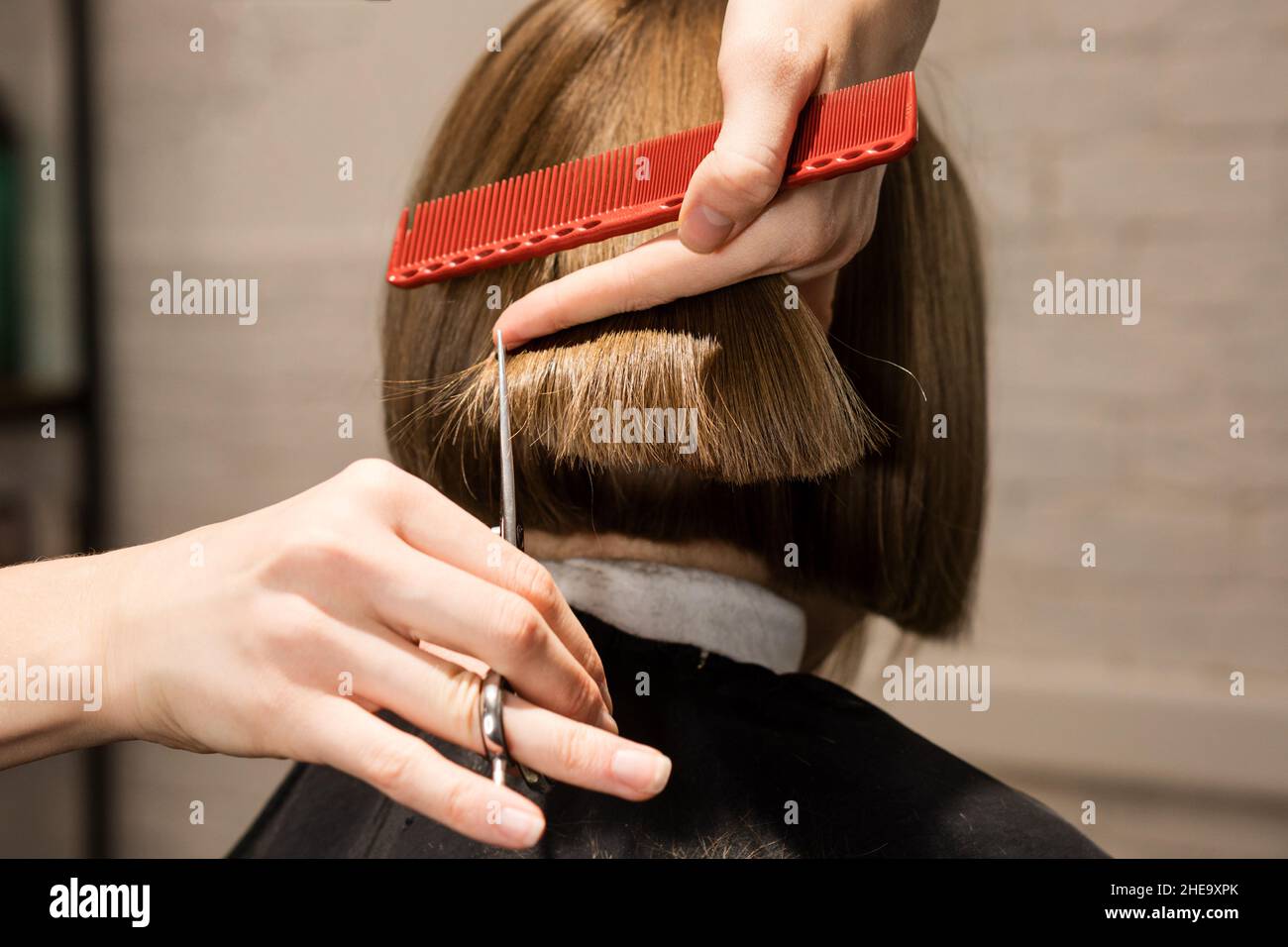 Gros plan arrière de la préadolescence fille assise dans la chaise dans le salon de coiffure. Coiffeur vérifiant sa nouvelle coupe de cheveux Banque D'Images