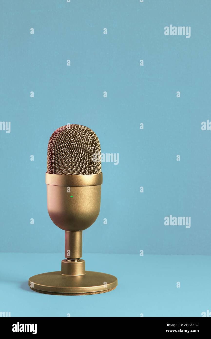 Microphone doré élégant et luxueux pour enregistrer sur un fond texturé pastel avec espace de copie.Concours et divertissement. Banque D'Images