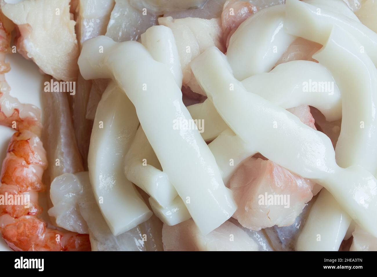 Gros plan sur des rondelles de calmar fraîches sur du merlu, du monkfish et des crevettes fraîches.Nourriture saine et poisson. Banque D'Images