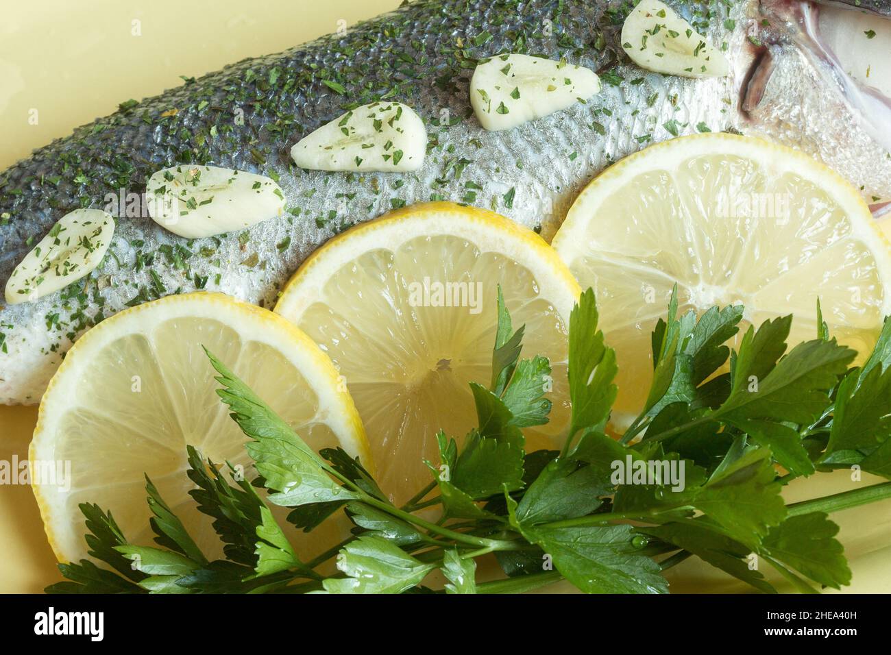 Ingrédients frais dans une plaque en céramique colorée préparée pour aromatiser le bar de mer frais.Épices, poisson et agrumes. Banque D'Images