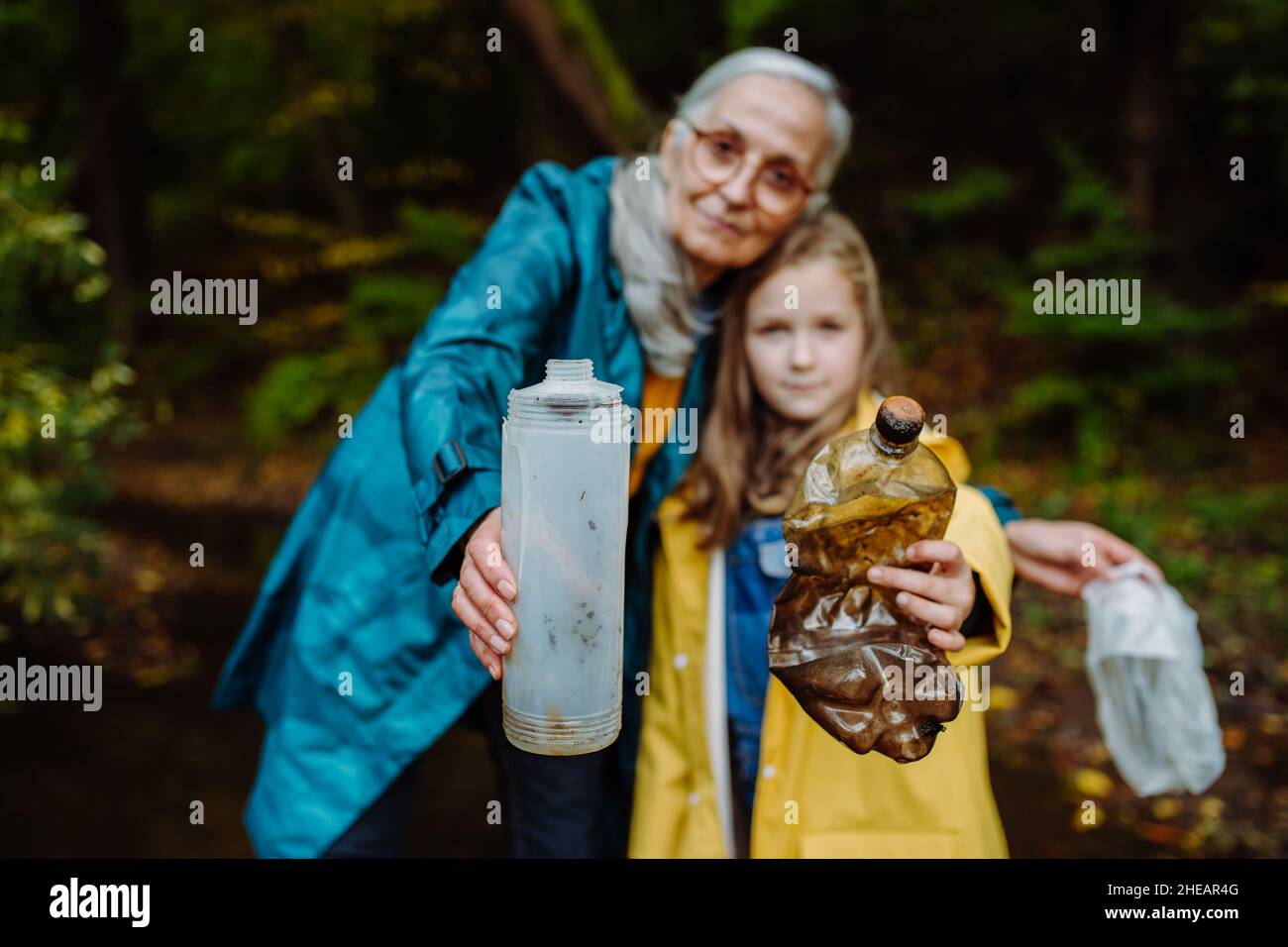 Petite fille avec grand-mère montrant les déchets de plastique ce qu'ils ont trouvé des outoors en forêt. Banque D'Images