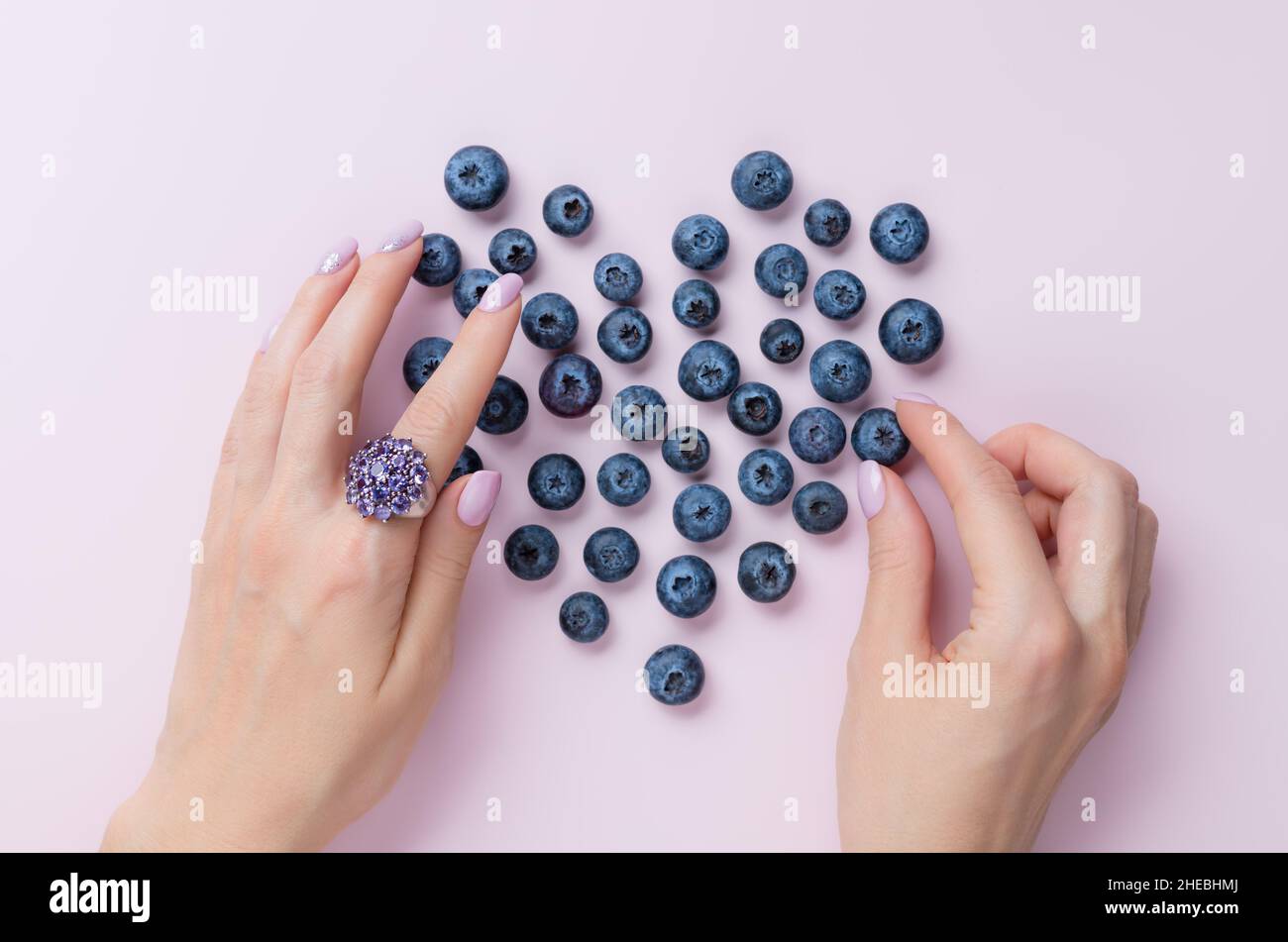 les mains de femmes avec une belle manucure faisant le coeur avec des bleuets Banque D'Images