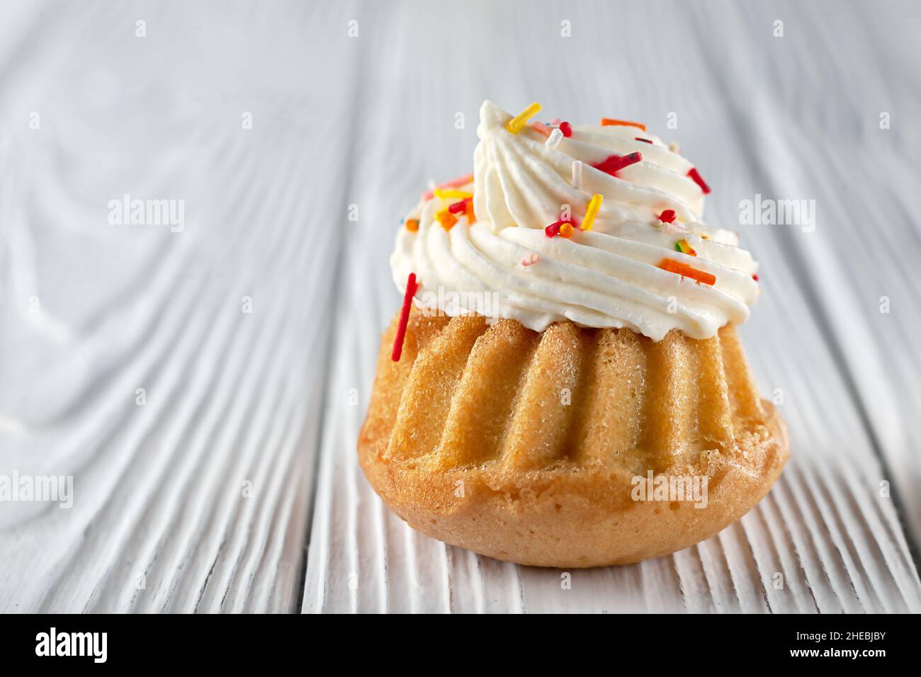 Muffins à la vanille avec crème au fromage à la crème et jus de caramel sur fond de bois.Copier l'espace. Banque D'Images