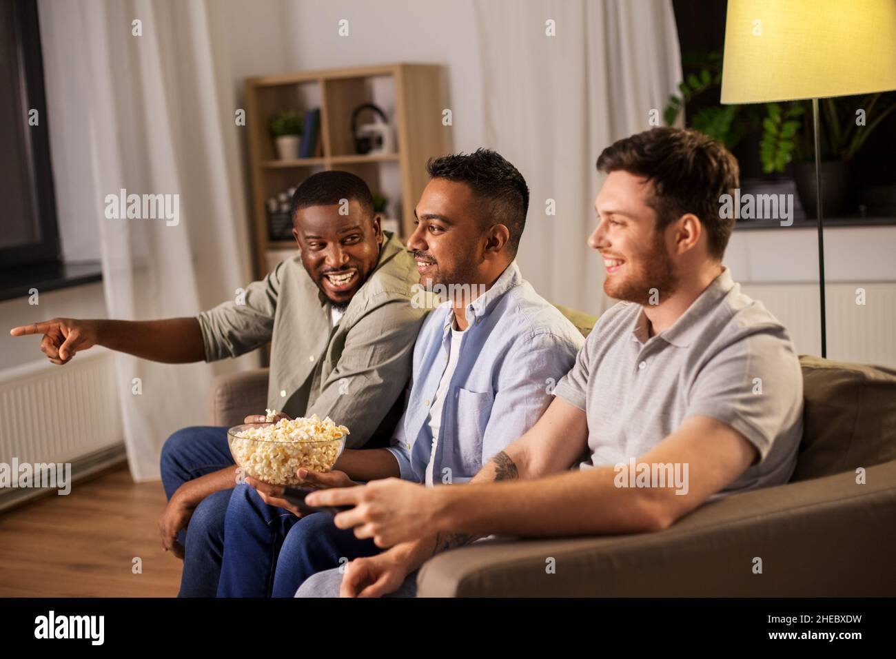 amis masculins avec pop-corn regardant la télévision à la maison Banque D'Images
