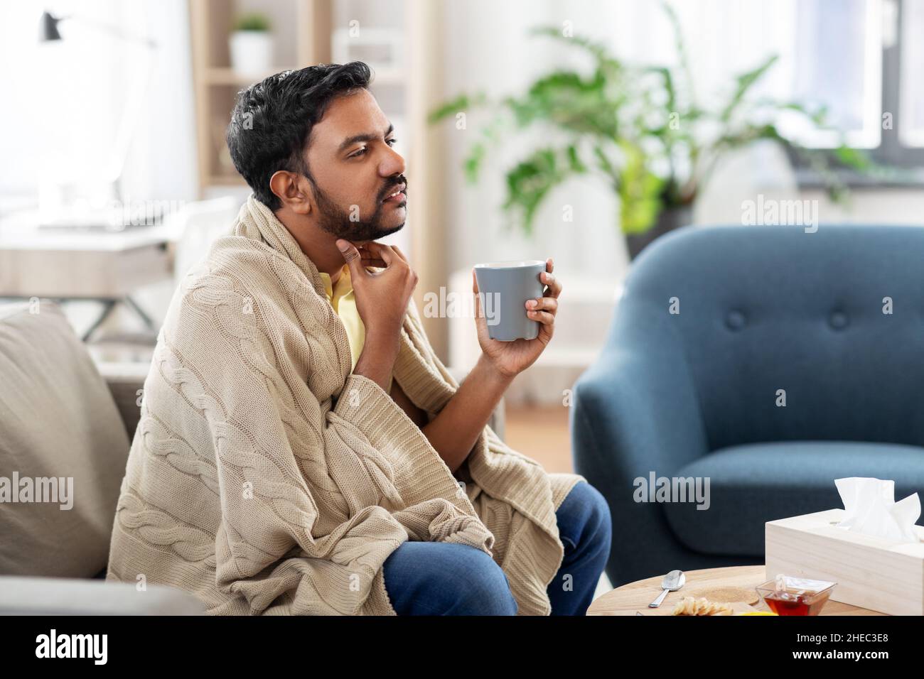 homme malade avec le thé touchant son mal de gorge à la maison Banque D'Images