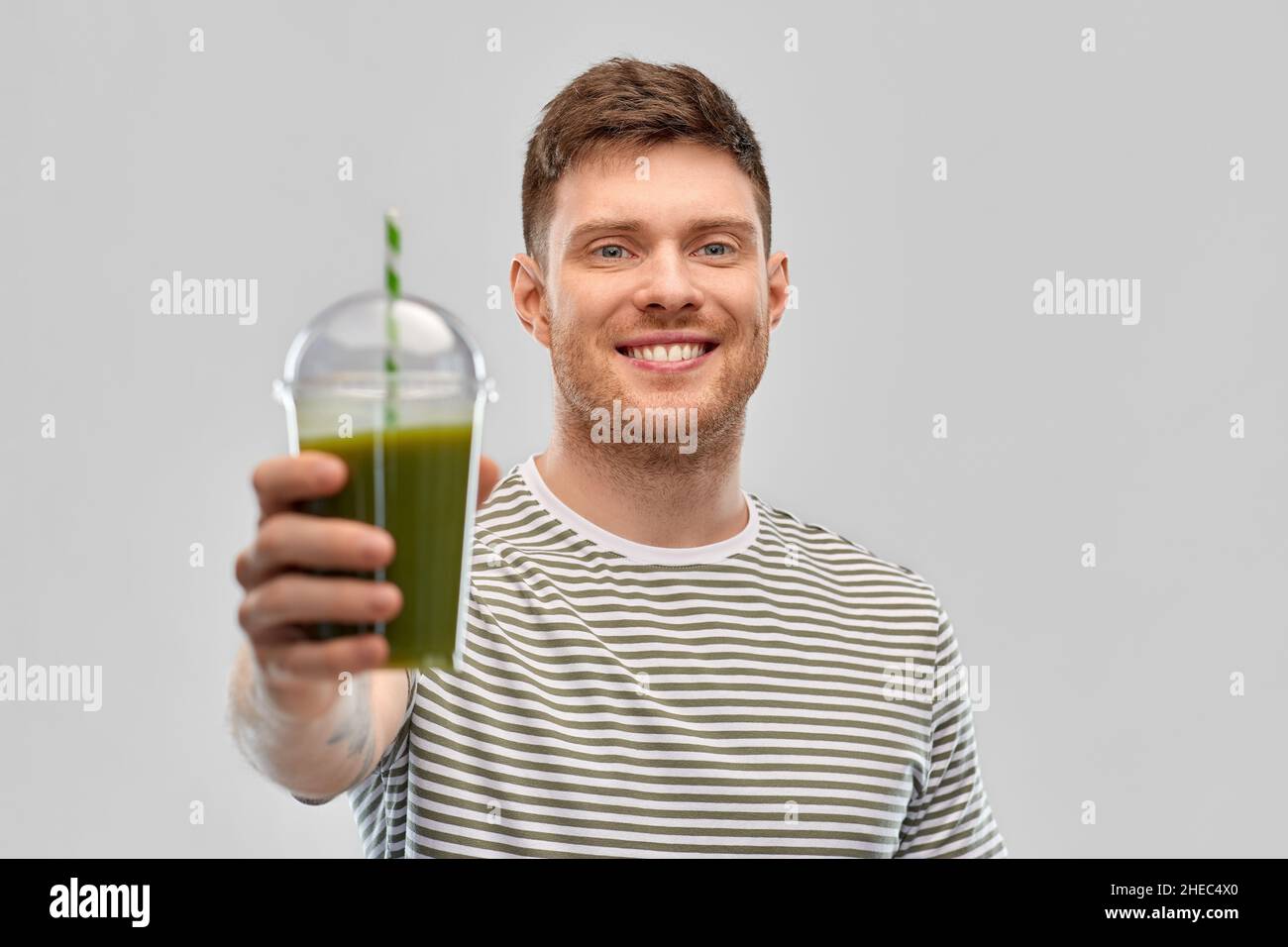 homme buvant du smoothie vert dans une tasse jetable Banque D'Images