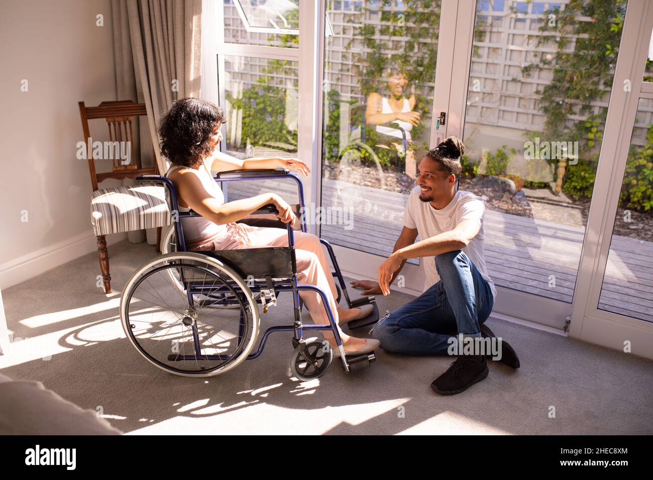 Femme afro-américaine handicapée en fauteuil roulant parlant à son mari à la maison Banque D'Images
