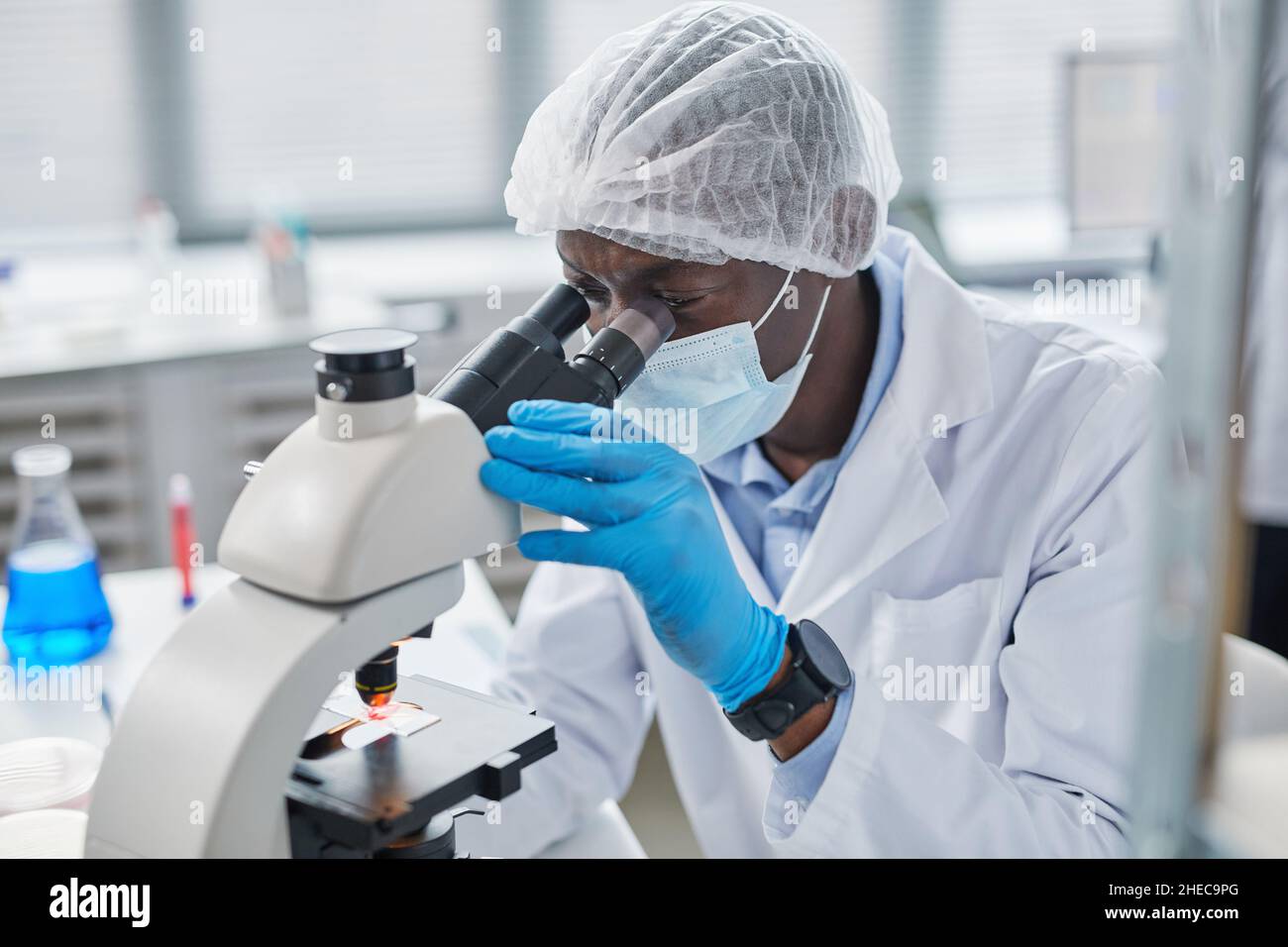 Chercheur biochimique travaillant avec un microscope pour le développement de vaccins coronavirus dans la recherche pharmaceutique labratoire Banque D'Images