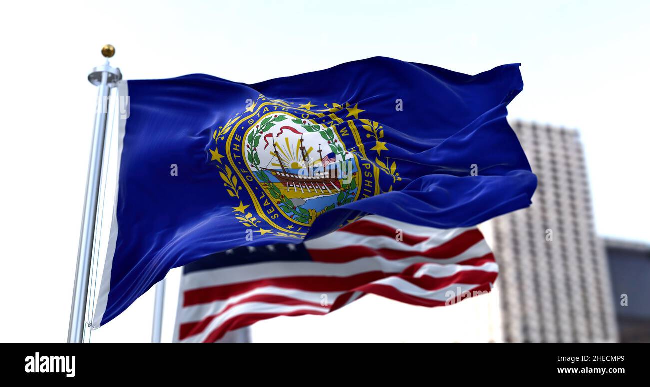 Le drapeau de l'état américain du New Hampshire agitant dans le vent avec le drapeau américain flou dans l'arrière-plan.Le New Hampshire a été admis à l'Union Banque D'Images