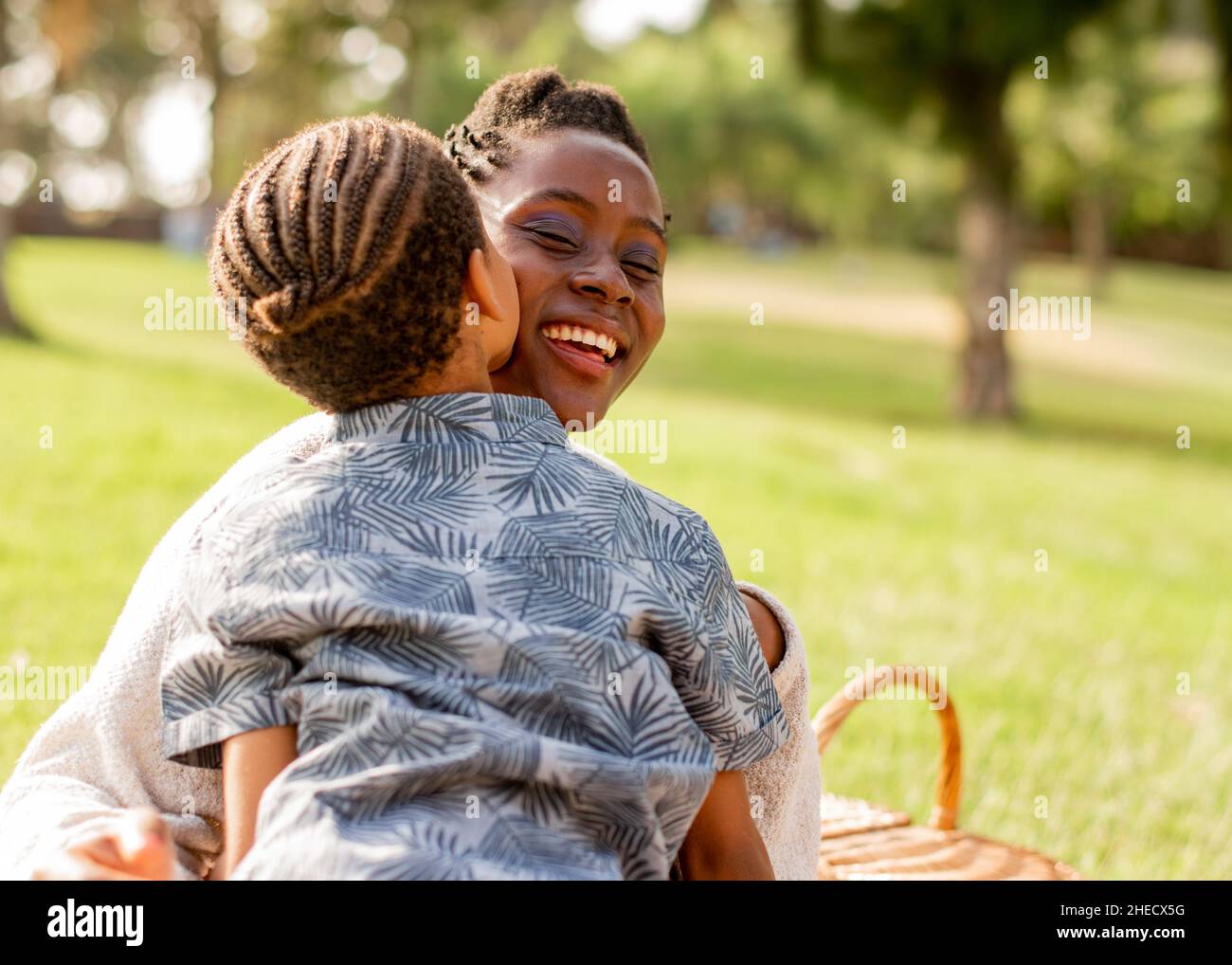 Anonyme enfant noir embrassant maman souriante pendant le pique-nique dans la nature Banque D'Images