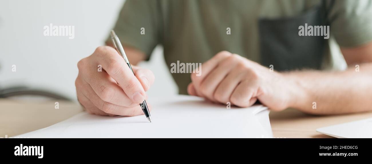 Télétravail écrivant des notes de projet dans un bureau à domicile, image panoramique avec mise au point sélective Banque D'Images