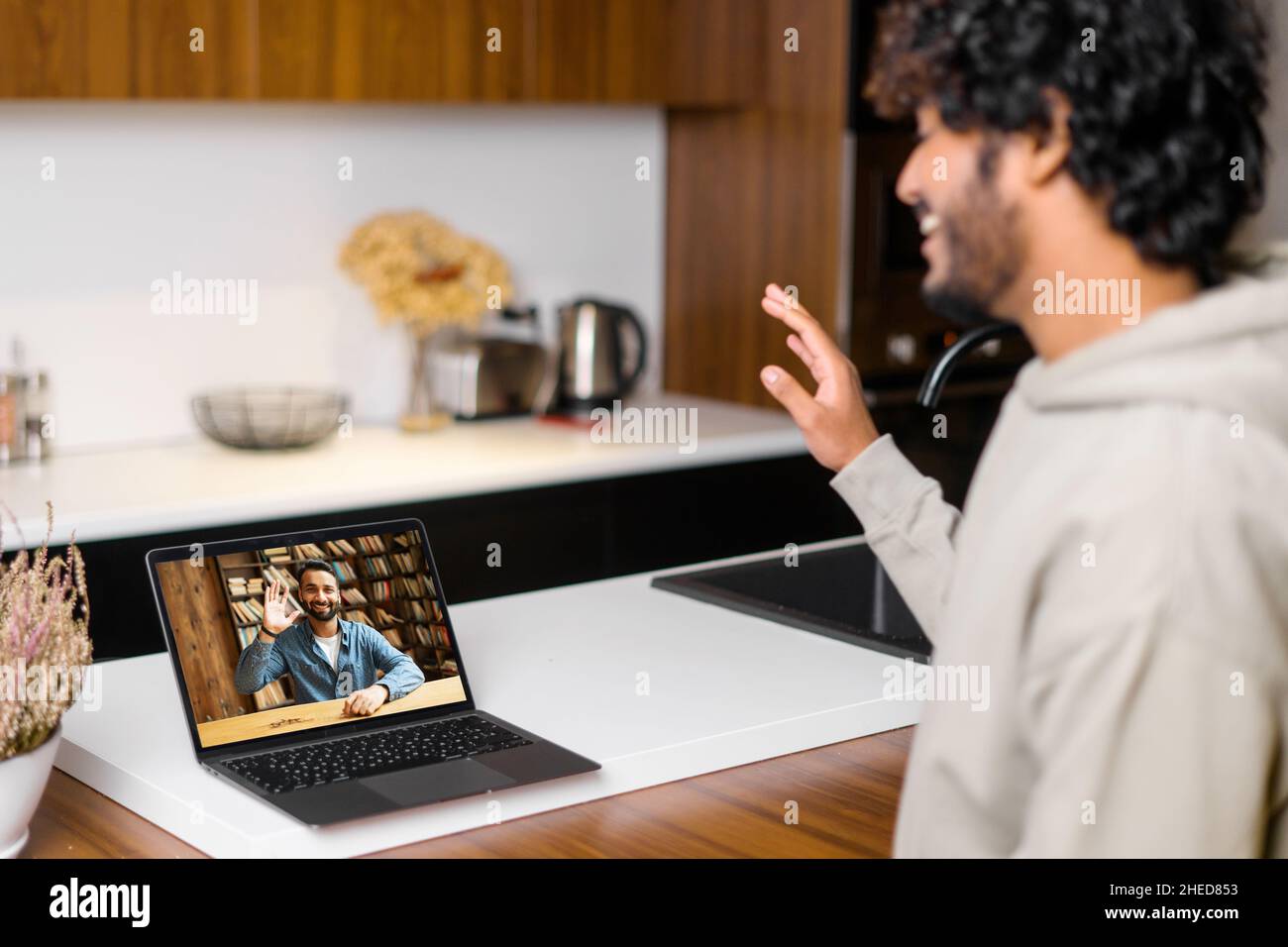 Gros plan de l'homme pakistanais utilisant l'application pour la communication vidéo à distance avec ses collègues, ses amis, la réunion en ligne, la recherche et l'agité sur un ordinateur portable avec des profils de personnes Banque D'Images