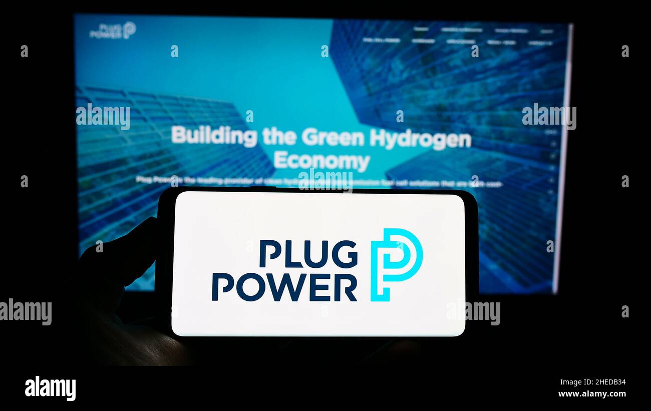 Personne tenant un téléphone portable avec le logo de la société américaine de piles à hydrogène Plug Power Inc. À l'écran devant la page Web.Mise au point sur l'affichage du téléphone. Banque D'Images