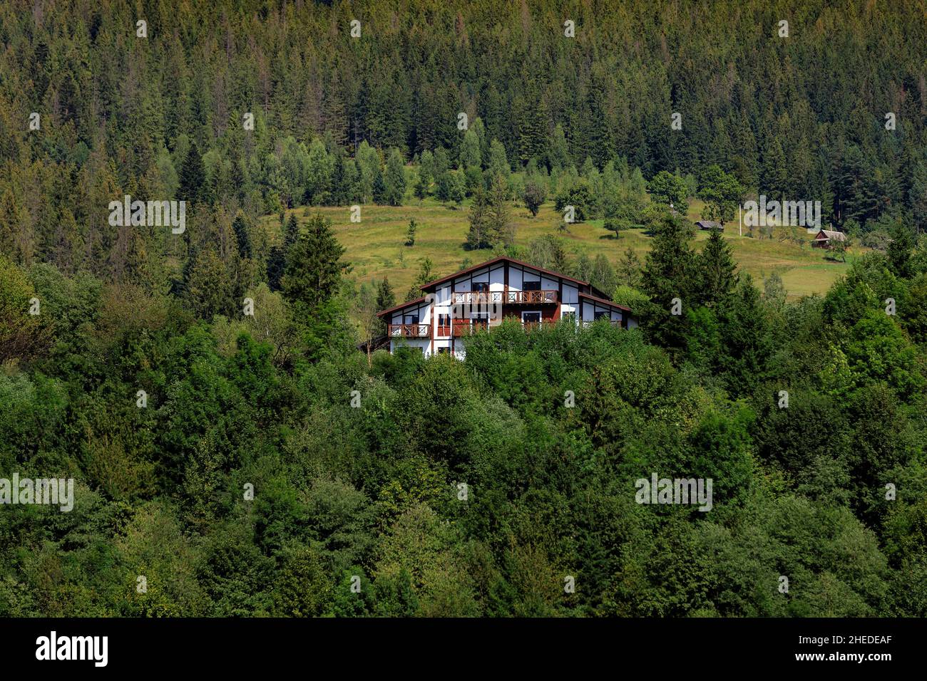 Maisons en bois dans les montagnes au milieu de la forêt, sur une pente, nuages et ciel bleu.Carpates Banque D'Images