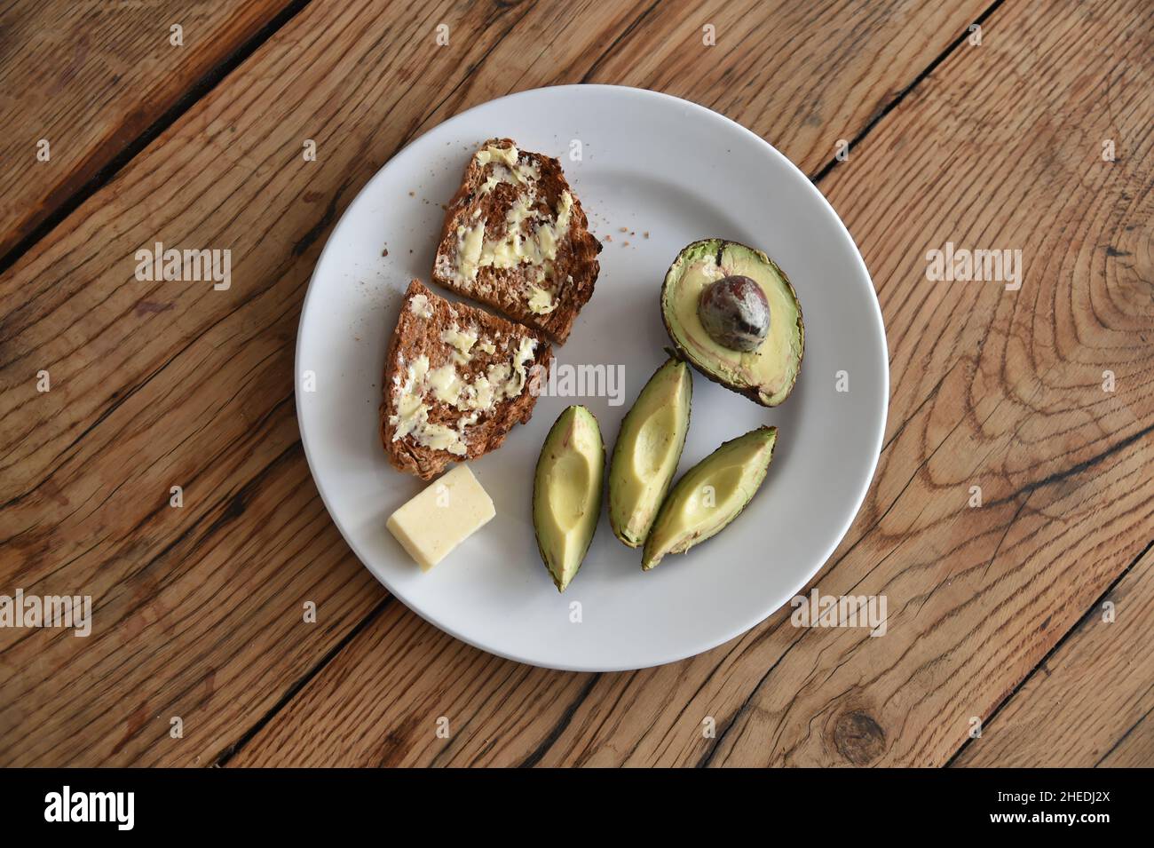 Avocat tranché sur une table en bois dans une assiette blanche Banque D'Images
