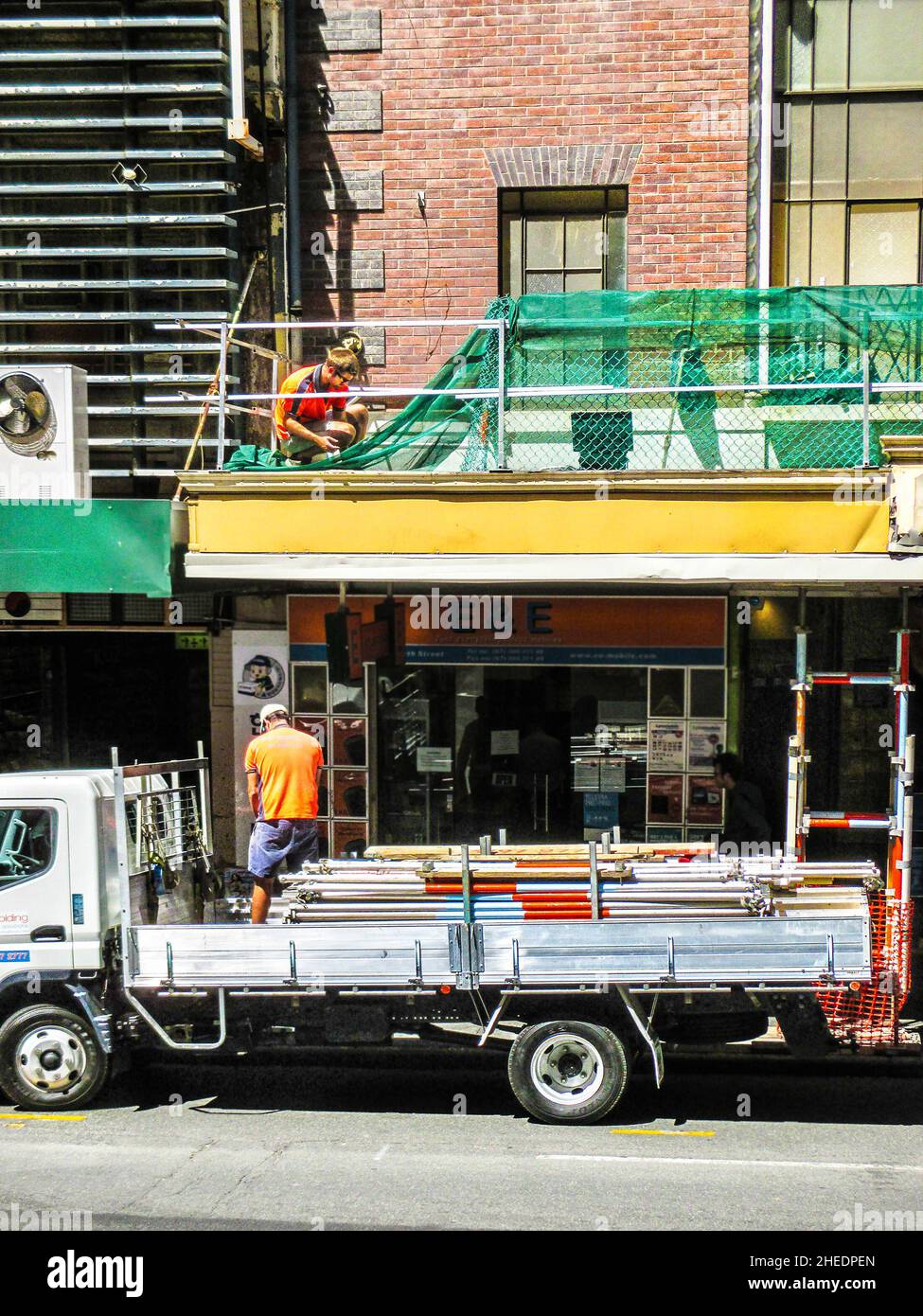 09-2014 Brisbane Australie - travaux de réparation sur un bâtiment en ville - un sur un balcon et un sur un camion en dessous rempli de tuyaux Banque D'Images