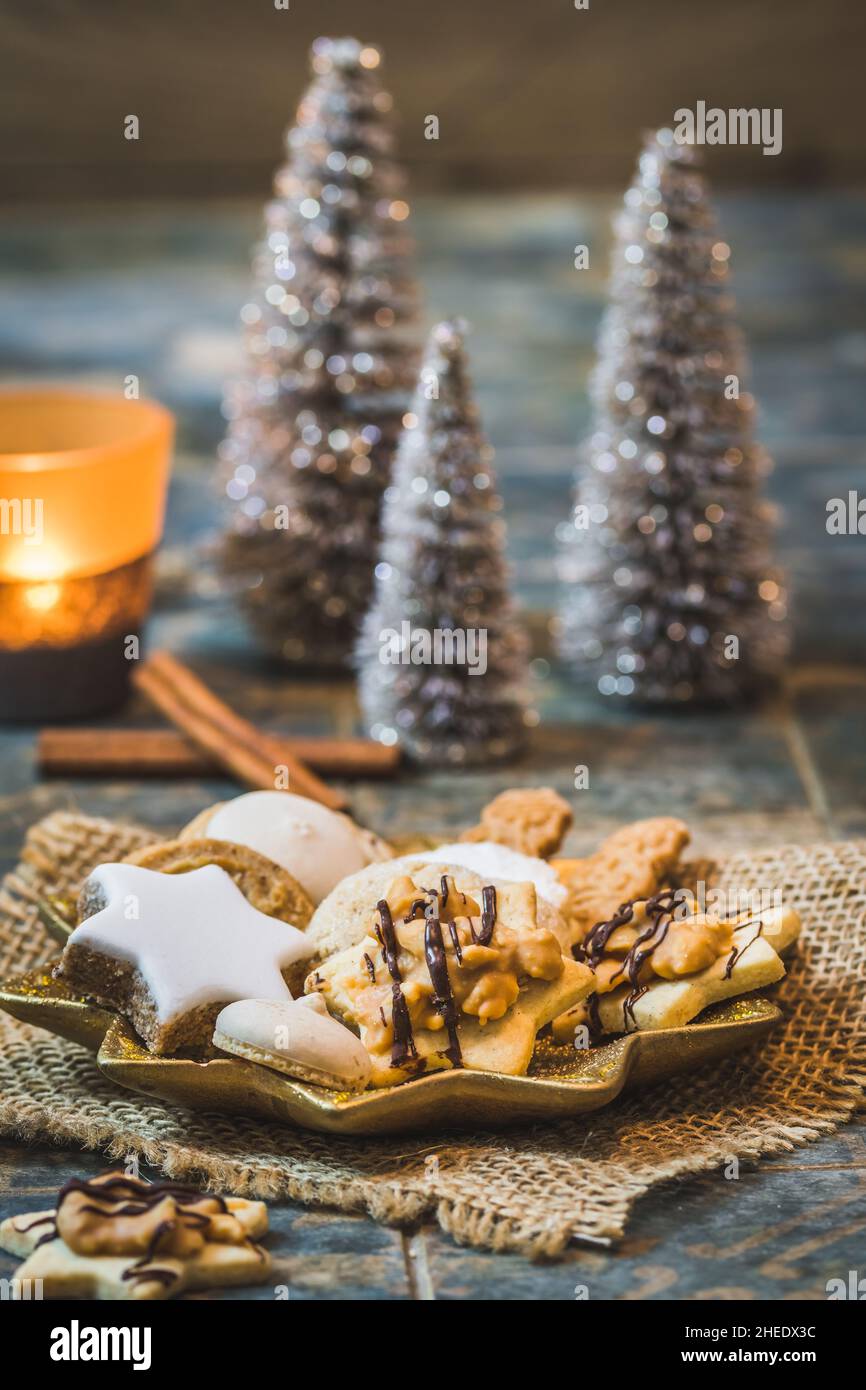 Biscuits de Noël sur une assiette en forme d'étoile avec décoration de noël et bougie lumineuse, verticale Banque D'Images