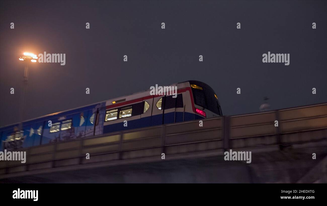 Paysage urbain en arrière-plan, métro approchant la gare sur la droite, passant par le pont au crépuscule.Vidéo.Station de métro surface Banque D'Images