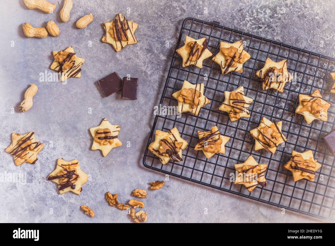 Biscuits faits maison en forme d'étoile avec garniture caramel aux noix et chocolat, sur un panier rafraîchissant et fond gris, vue du dessus Banque D'Images