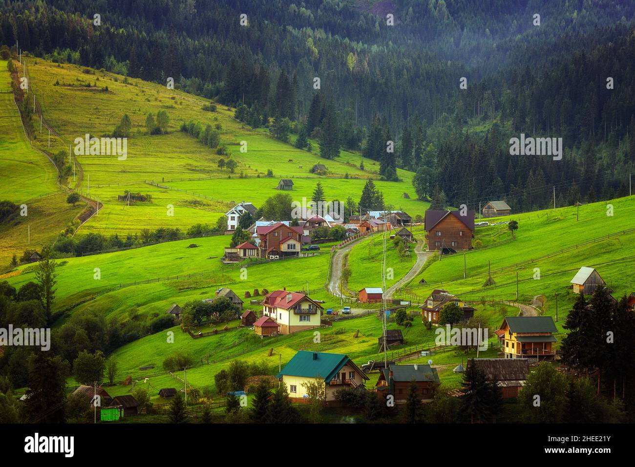 Maisons en bois dans les montagnes au milieu de la forêt, sur une pente, nuages et ciel bleu.Carpates Banque D'Images