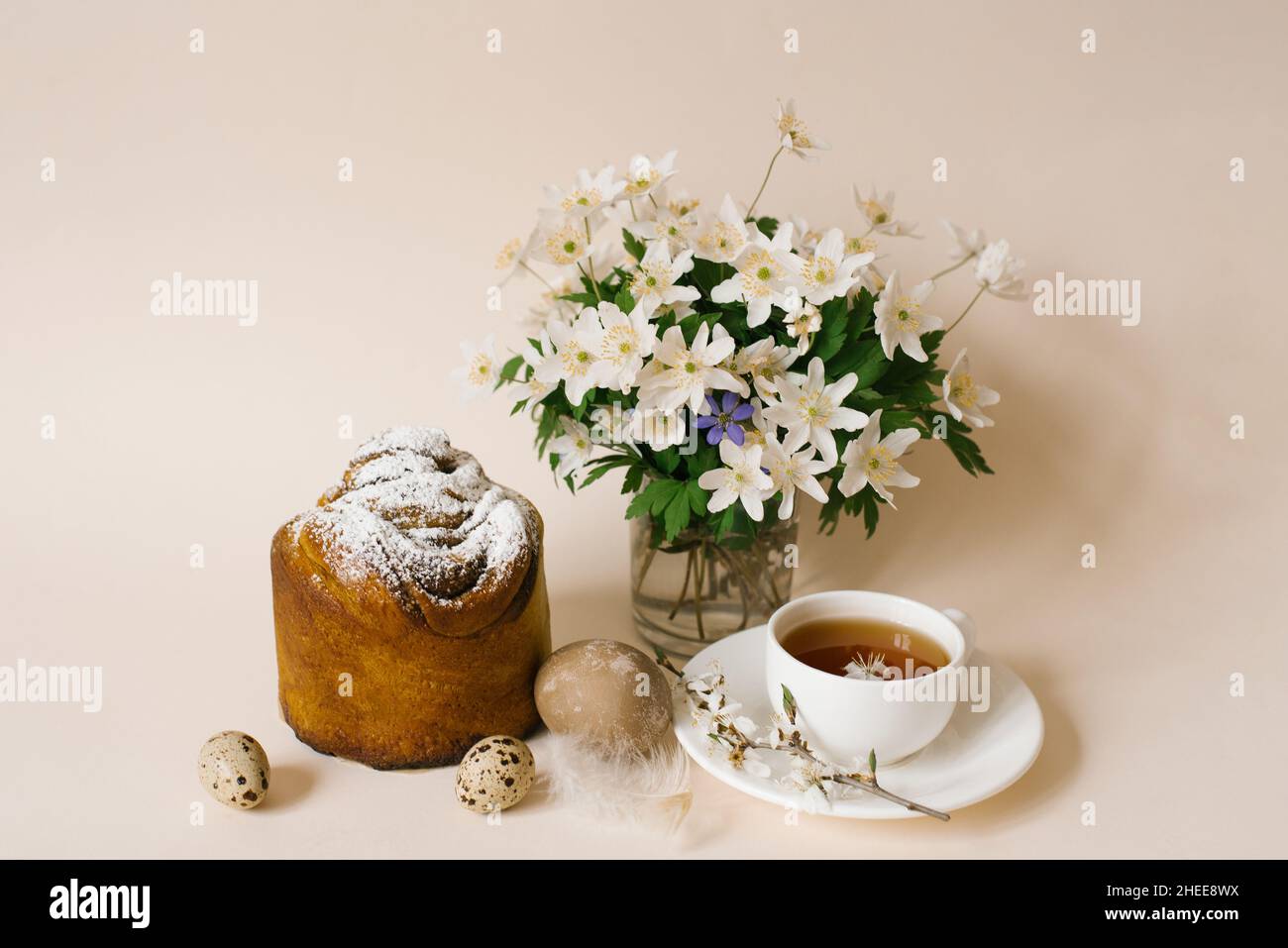 Gâteau de Pâques à l'intérieur. Faites de la spécialité avec des raisins secs, des fruits confits et une saupoudré de sucre. Gâteau fait maison. Oeufs, une tasse de thé et fleurs de printemps dans un v Banque D'Images