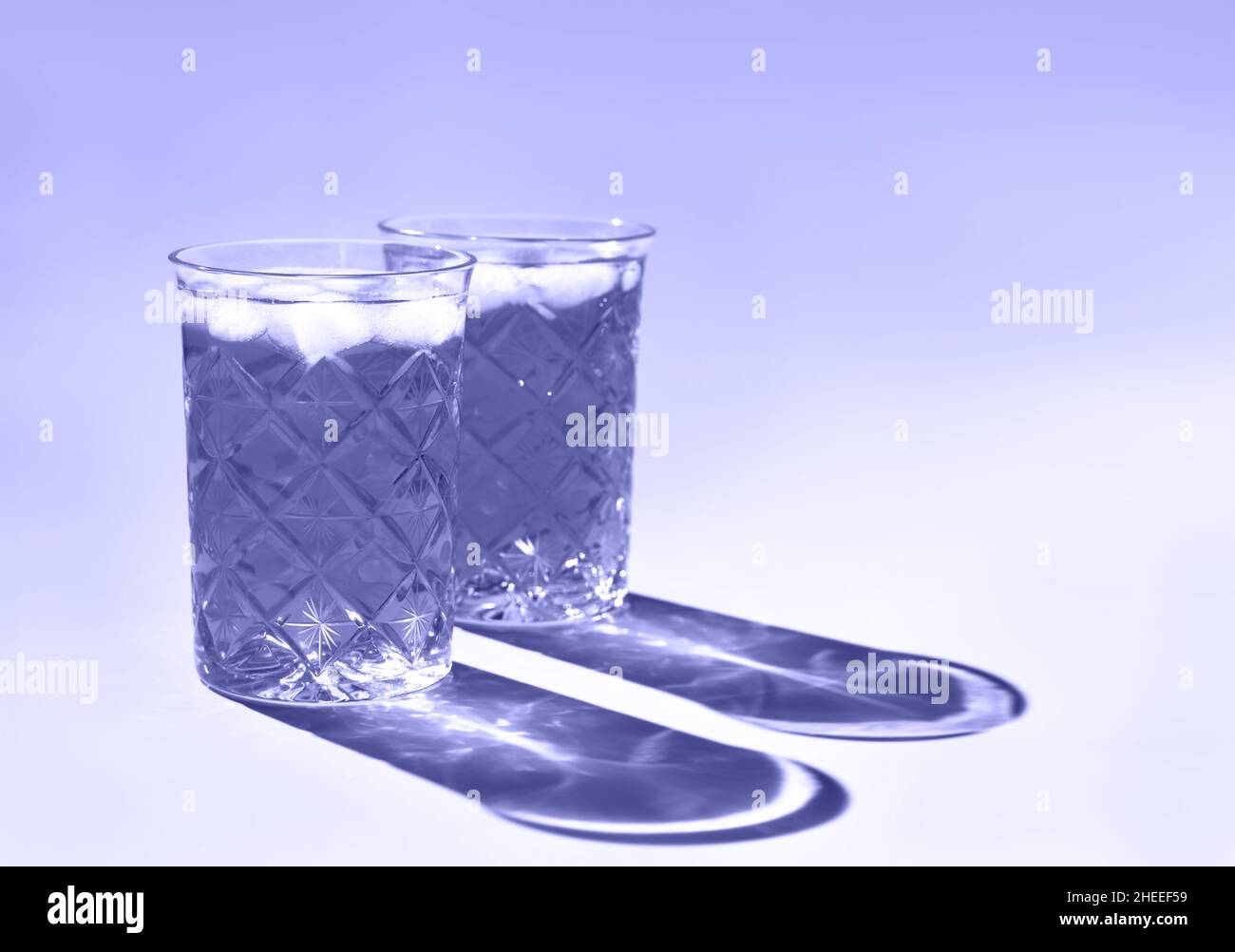 De magnifiques verres en cristal jettent une ombre longue de la lumière du soleil.Coloris tendance de l'année 2022.Composition créative minimale avec espace de copie.Concept des boissons d'été. Banque D'Images