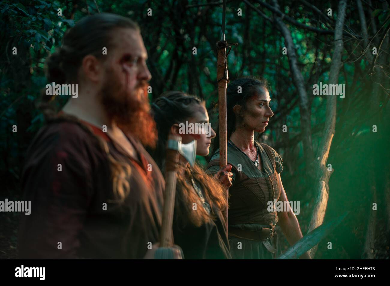Des hommes et des femmes ont blessé des guerriers avec une épée et une lance haches pour lutter contre leur adversaire lors de la reconstitution historique dans les bois Banque D'Images