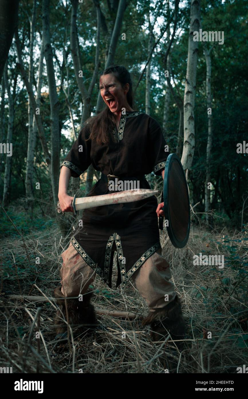 Une femme furieuse avec un poignard pointu et un bouclier couvert de sang  criant à haute voix pendant la reconstitution du combat viking dans la  forêt Photo Stock - Alamy
