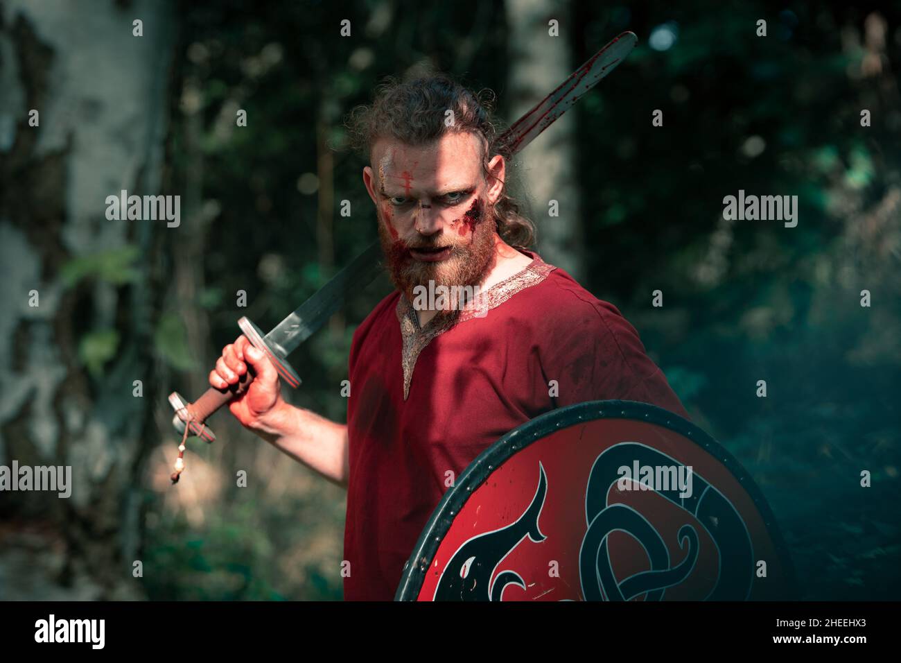 Un homme intrépide se défendant avec un bouclier et se tenant à l'épée pour se faire prendre en photo lors de la reconstruction médiévale de viking dans la forêt Banque D'Images