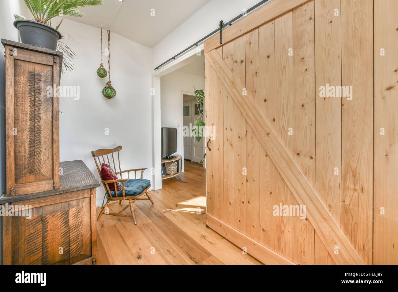 Chaise confortable à l'ancienne avec coussins placés dans la chambre avec armoire en bois vintage et portes coulissantes à la lumière du jour Banque D'Images