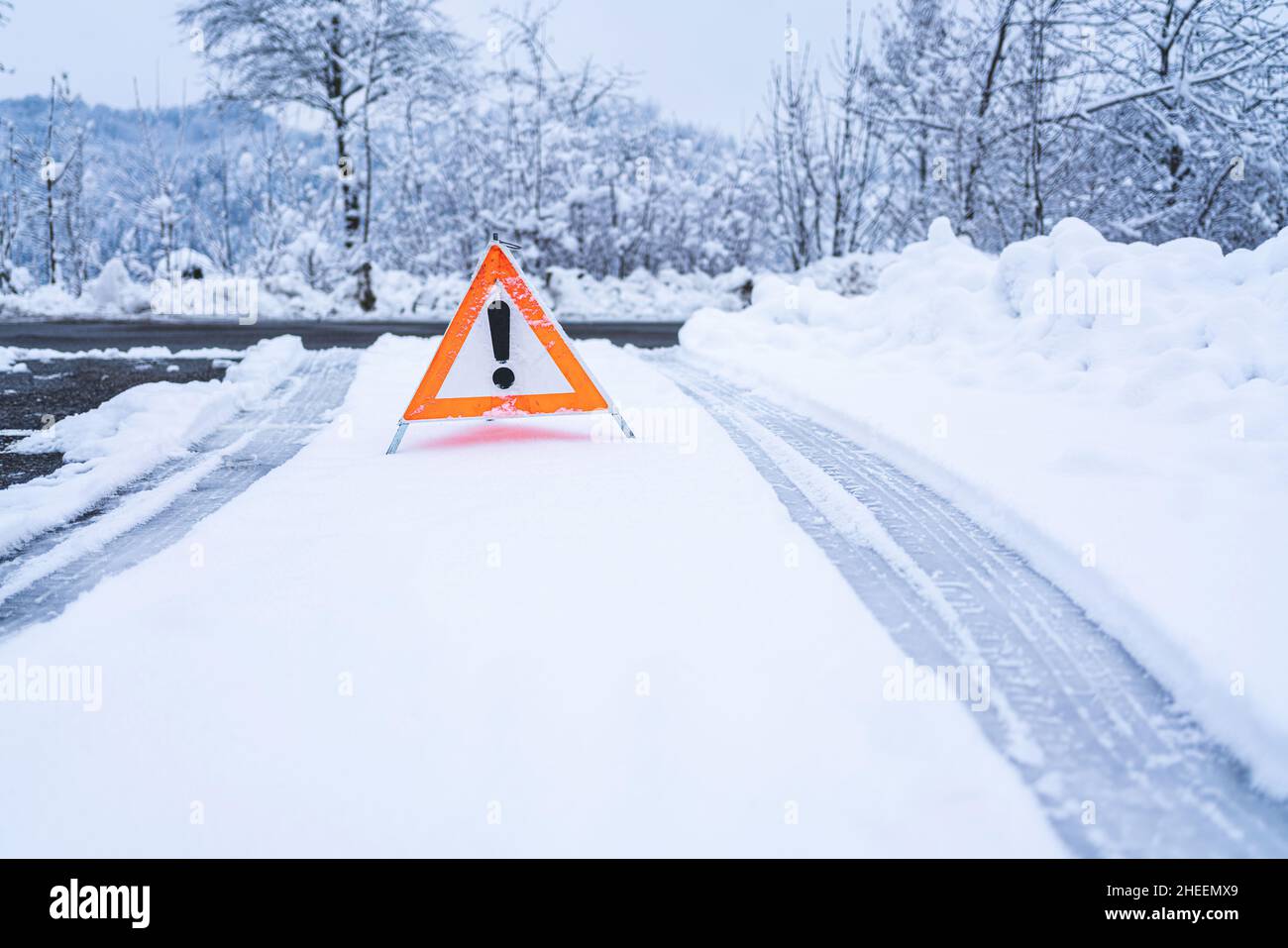 Un panneau de mise en garde signalant le danger de conduire dans la neige à cet endroit.Marques de pneu dans la neige. Banque D'Images