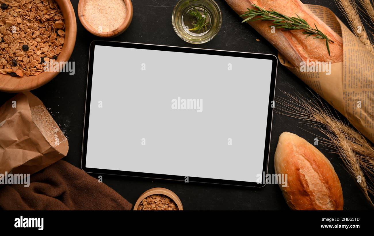 Tablette Mockup écran tactile pour monter votre bannière graphique avec du pain français, du pain cuit, de la farine, des grains entiers sur fond noir.Vue de dessus, plate Banque D'Images