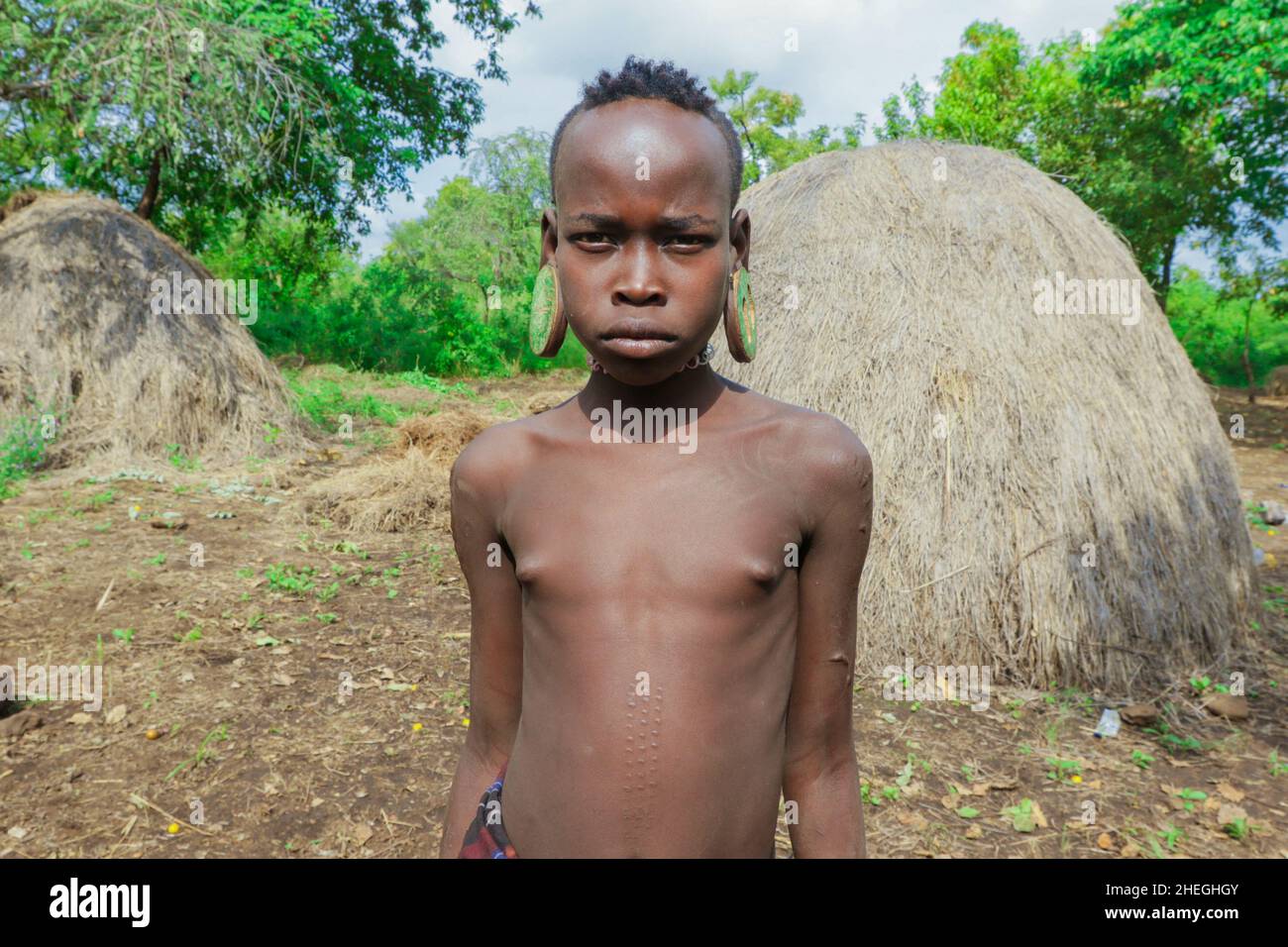 Vallée de la rivière Omo, Éthiopie - 29 novembre 2020 : portrait d'un adolescent africain avec de grandes boucles d'oreilles traditionnelles en bois dans le village de la tribu locale de Mursi Banque D'Images