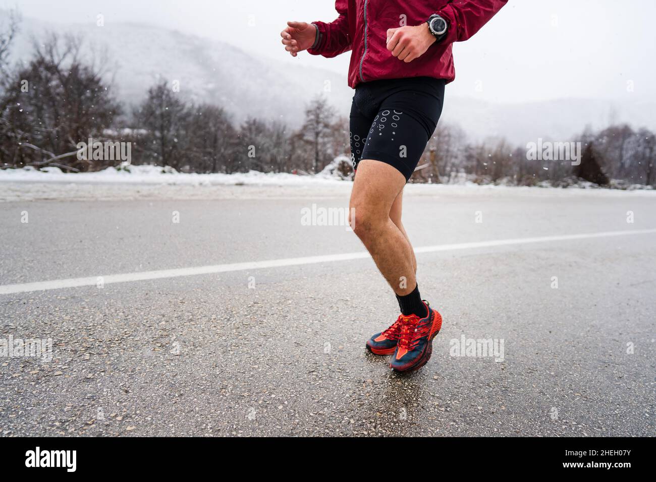 Un homme caucasien adulte courant en hiver jour athlète masculin entraînement sur la route ouverte dans la nature avec la neige santé et le concept de forme physique personnes réelles Banque D'Images