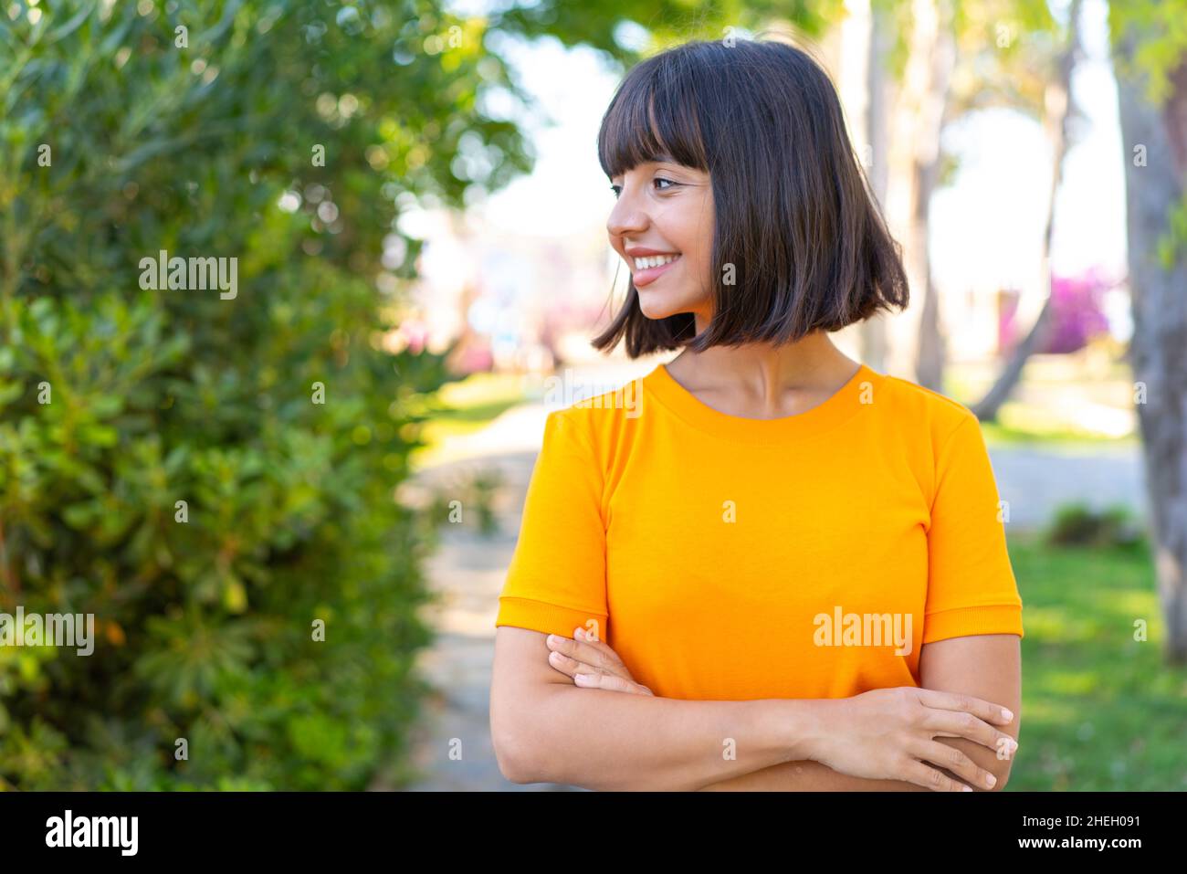 Jeune femme brune à l'extérieur dans un parc avec une expression heureuse Banque D'Images