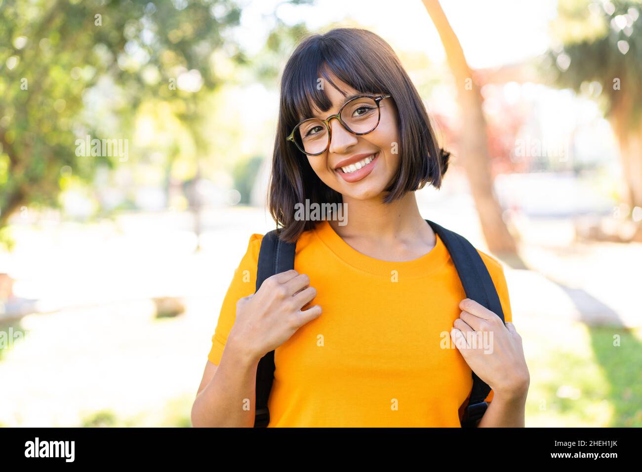 Jeune femme brune à l'extérieur avec une expression heureuse Banque D'Images