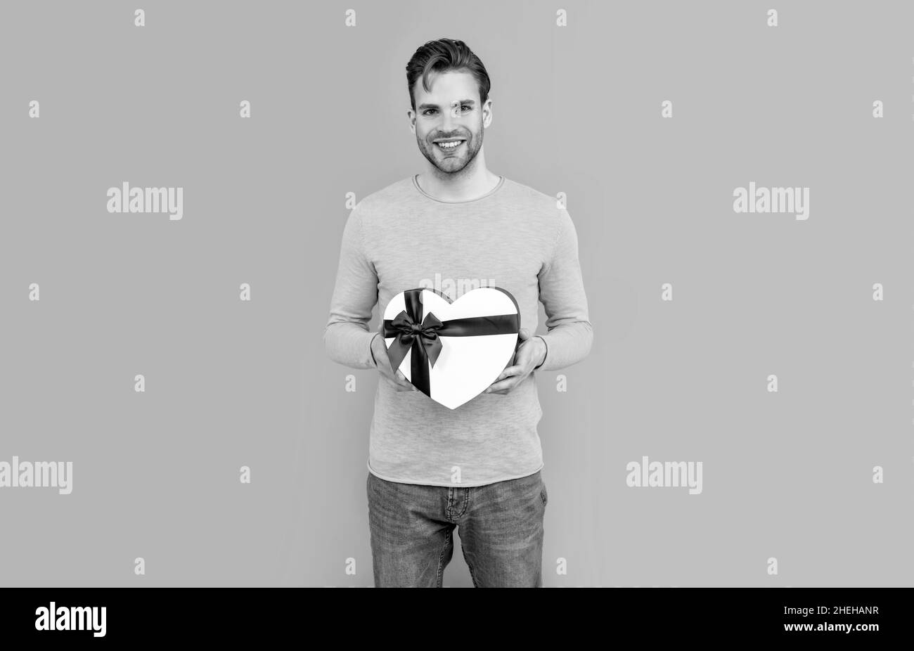 Bonne Saint Valentin. Un homme sourit tenant une boîte cadeau en forme de cœur. Saint Valentin présent Banque D'Images