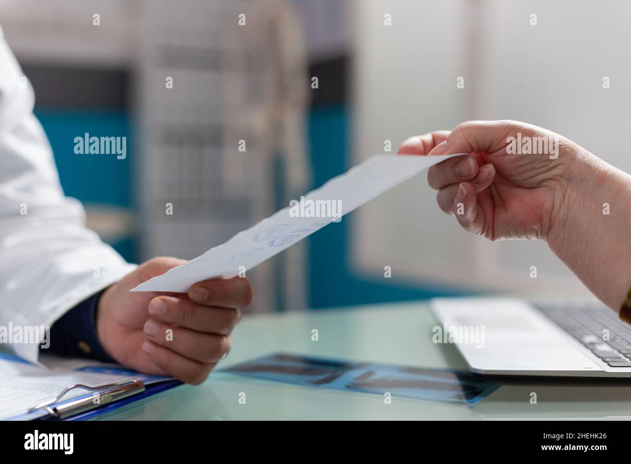 Médecin donnant le document de prescription au patient dans l'armoire, après consultation médicale.Rapport de contrôle de la tenue de Medic pour donner le traitement à la personne à la retraite dans le bureau de soins de santé.Gros plan Banque D'Images