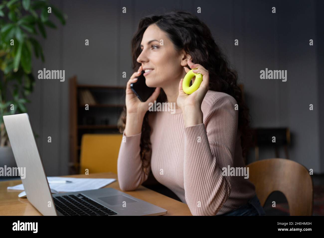 Jeune femme d'affaires faisant des exercices d'échauffement de main sur le lieu de travail, s'exerçant avec l'anneau de renforcement de poignée Banque D'Images