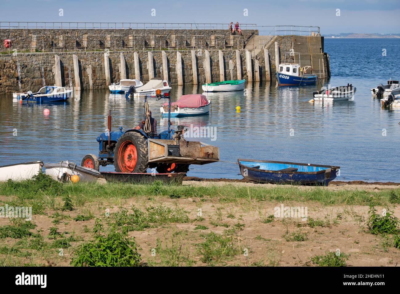 Un tracteur d'époque fait glisser un bateau à rames en bois à travers Trefor Beach, dans le nord du pays de Galles, pour être lancé Banque D'Images