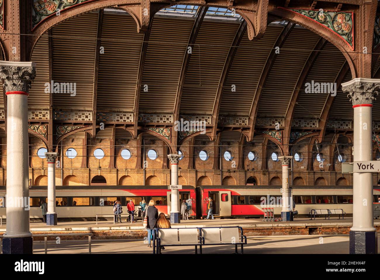 Les quais de la gare avec les passagers attendant un train.Le toit est un toit historique avec des colonnes de chaque côté. Banque D'Images