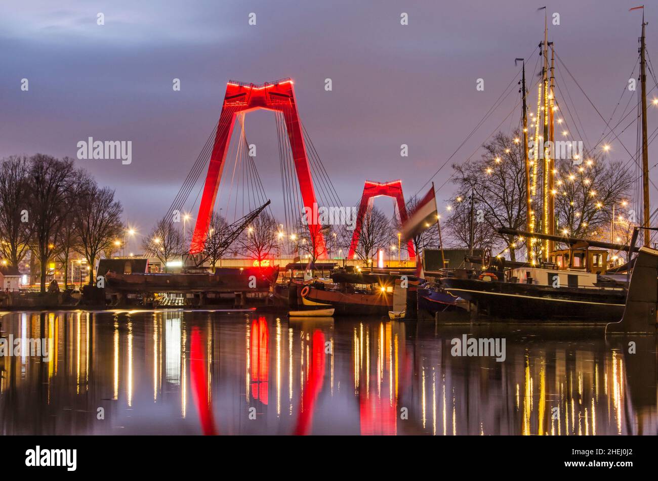 Rotterdam, pays-Bas, 7 janvier 2022 : les pylônes rouges du pont Willems s'élèvent au-dessus des barges historiques dans le vieux port, dans le bec bleu de l'heure Banque D'Images